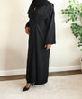 Load image into Gallery viewer, Image of a model wearing a classic black open abaya. The abaya can be styled open or closed, making it versatile for any occasion. It&#39;s perfect for all seasons and can be easily dressed up or down for a chic look
